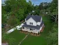 Inviting two-story home with a charming front porch, lush lawn, and a long driveway at 61 Main St, Moreland, GA 30259
