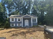 Charming home featuring a painted brick facade, white shutters, and a well-manicured lawn at 8427 Fredericksburg Ct, Jonesboro, GA 30238