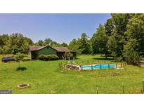 Charming home with a pool, surrounded by lush greenery and a spacious yard, perfect for outdoor living at 1828 Pitts Chapel Rd, Newborn, GA 30056