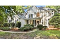 Elegant two-story home featuring a stucco facade, black shutters, and manicured landscaping at 1202 Loxley Cir, Peachtree City, GA 30269