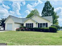 Charming single-story home featuring a well-manicured lawn and an attached garage at 486 Village Cir, Stockbridge, GA 30281