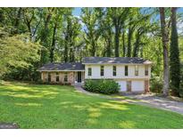 Charming two-story home with brick accents, a well-manicured lawn, and mature trees surrounding the property at 5802 Simone Dr, Stone Mountain, GA 30087