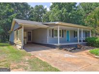 Charming single-story home with a covered front porch, carport, and a bright blue front door at 315 Charlotte Blvd, Stockbridge, GA 30281