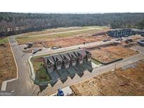 An aerial view shows newly constructed townhomes with individual driveways and a partially developed community surrounding it at 120 Meadowview Dr # 10, Temple, GA 30179