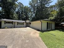 Charming one-story brick home with an attached two car garage, a well-manicured lawn, and mature trees at 421 Safari Cir, Stone Mountain, GA 30083