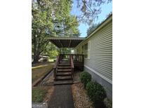 View of a covered wooden back porch with stairs leading down to a manicured yard at 85 North Ave, Hampton, GA 30228