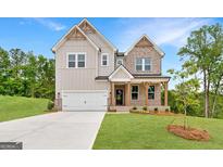 Inviting two-story home boasts a 2-car garage, a blend of gray siding, brick accents, and a covered front porch at 7530 W Homer Dr, Cumming, GA 30028