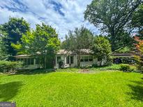 Charming single-story home with lush green lawn and mature trees, creating a serene setting at 4160 Stonewall Tell Rd, Atlanta, GA 30349