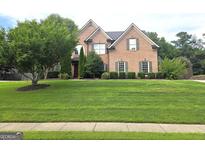 Charming two-story brick home with well-manicured lawn and mature landscaping at 910 Lilac Arbor Rd, Dacula, GA 30019