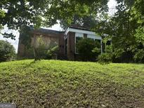 A single-story brick home features large windows, but the lawn and some windows need tending to at 1175 Monroe Ne Dr, Atlanta, GA 30306