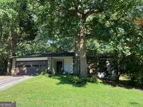 Charming single-story home with a stone facade, mature trees and a well-manicured lawn at 215 Lakeland Ct, Roswell, GA 30076