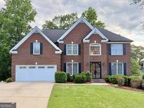 Stately brick home with a manicured lawn and a two-car garage at 6765 Crofton Dr, Alpharetta, GA 30005