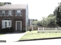 Charming brick two-story home with a well-maintained lawn and a white picket fence at 2116 Charter Ln, Lithonia, GA 30058