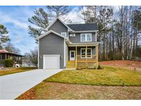 Charming two-story home with gray siding, a front porch, manicured lawn, and an attached garage at 192 Pecan Dr, Canton, GA 30114