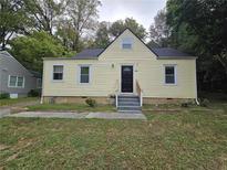 Charming home with yellow siding, black door, and well-maintained lawn at 403 Forrest Ridge Nw Dr, Atlanta, GA 30318