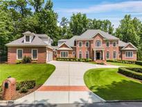 Stately brick home featuring a circular driveway, attached garage, and lush landscaping at 1655 Arrowhead Ne Trl, Atlanta, GA 30345