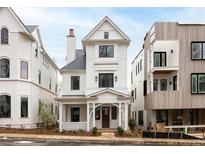 Charming three-story home featuring a welcoming front porch, classic white siding, and black framed windows at 11536 Serenbe Ln, Chattahoochee Hills, GA 30268