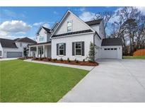 Beautiful white brick home with black trim, well-manicured lawn and attached garage on a sunny day at 6670 Benchwood Path, Cumming, GA 30028