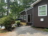 Charming exterior view of the lake house, featuring a front patio with a table, chairs, and a well-maintained yard at 7 Yachting Way, Acworth, GA 30102