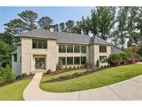 Beautiful stone home featuring manicured landscaping, gray shingles, and modern windows at 825 Kenry Ct, Atlanta, GA 30342