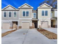 Charming townhouse with attached garages, brick accents and manicured lawns, set against a bright blue sky at 6104 Ripple Way # 50, South Fulton, GA 30349