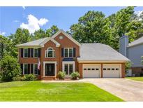 Charming two-story brick home featuring a two-car garage, manicured lawn, and classic black shutters at 4284 Windy Gap Nw Ct, Kennesaw, GA 30144