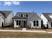 Charming single-story home featuring a black metal roof accent, white siding, and a well-maintained lawn at 505 Godfrey Dr, Cumming, GA 30040