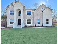 Beautiful two-story home with white brick, arched entry, and a neatly manicured front lawn at 179 Basie Ct, Fairburn, GA 30213