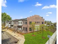Stunning new townhomes with brick facade and manicured lawns sit under a bright blue sky at 945 Willingham Dr # 3, Hapeville, GA 30354