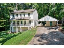 Two-story house with front porch and carport, nestled in a wooded area at 105 Woodmeade Nw Way, Marietta, GA 30064