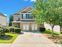 Charming two-story brick home featuring a well-manicured lawn, mature tree, and a spacious driveway at 2319 Sawgrass Rd, Hampton, GA 30228