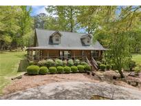 Charming log cabin home with a covered porch and well-manicured landscaping for a welcoming curb appeal at 3208 Paddock Rd, Covington, GA 30014