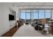 Bright living room with hardwood floors, large windows, and city views at 1065 Peachtree Ne St # 3003, Atlanta, GA 30309