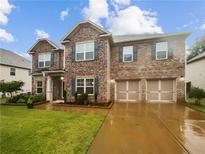 Charming two-story home featuring a mix of stone and brick, attached two-car garage, and manicured lawn at 3650 Lindsy Brooke Ct, Douglasville, GA 30135