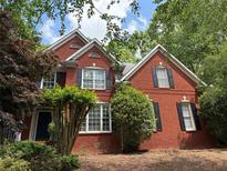 Charming two-story red brick home featuring classic black shutters and lush, mature landscaping at 2631 Gladstone Ter, Woodstock, GA 30189