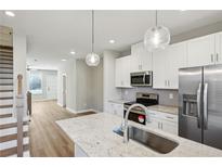 Bright kitchen features stainless appliances, white cabinets, granite countertops, and modern globe pendant lights at 1095 Tucker Ave # 401, Atlanta, GA 30310