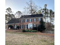 Charming brick two-story home with a manicured front yard featuring daffodils and mature trees at 2921 Wickford Nw Dr, Kennesaw, GA 30152