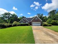 Charming single-story brick home with a well-manicured lawn and a two-car garage on a sunny day at 7030 Valley Landing Ct, Cumming, GA 30041