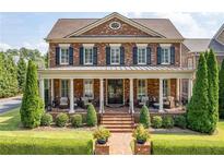 Brick two-story house with a large front porch and landscaped yard at 8025 Georgetown Cir, Suwanee, GA 30024