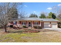 Brick ranch house with attached double garage, front porch, and landscaped yard at 2805 Bridle Se Path, Conyers, GA 30094