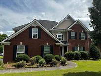 Traditional brick two-story home with dark shutters, manicured landscaping, and a curved walkway at 989 Park Knoll Ct, Lawrenceville, GA 30043