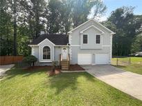 Charming split-level home with a well-manicured lawn and an inviting entrance with an arched window at 320 Rebecca Lake Way, Fairburn, GA 30213