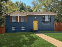 Charming blue home with a well-manicured lawn, yellow front door, and beautiful bay window at 226 Stayman Dr, Riverdale, GA 30274