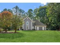 Charming gray two-story home with a manicured lawn and mature trees offering curb appeal at 1210 Swan Mill Ct, Suwanee, GA 30024