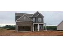 Two-story home featuring a stone facade, an attached garage, and covered front porch at 5994 Spring Way, Stonecrest, GA 30038