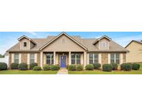 Charming brick home featuring manicured landscaping, a welcoming blue front door, and light-filled windows at 1129 Abundance Dr, Locust Grove, GA 30248