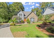 Inviting home featuring a stone facade, complemented by a lush green lawn and a winding walkway to the front door at 7445 Talbot, Sandy Springs, GA 30328