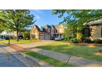 Beautiful brick home featuring a manicured lawn and a spacious driveway leading to a three-car garage at 3450 Camellia Ln, Suwanee, GA 30024