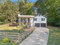 White house with black accents, two-car garage, and fenced yard at 179 Village Dr, Hiram, GA 30141
