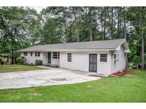 Charming one-story home with a concrete driveway and a lush, green lawn surrounded by mature trees at 1705 Atherton Dr, Decatur, GA 30035